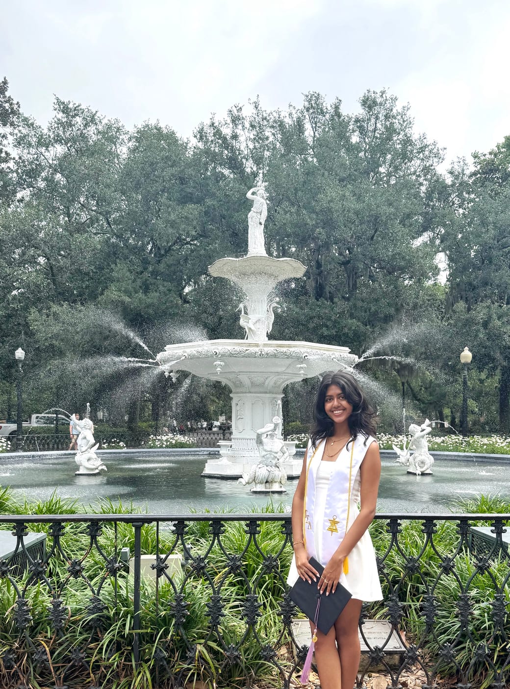 Khushi Patel in front of the Forsyth Park fountain in Savannah, in graduation dress holding her cap